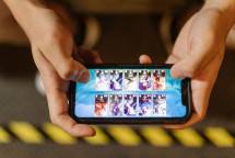Close-up of hands playing a mobile game on a smartphone, showcasing the game's interface. (Foto: RDNE Stock project / Pexels)